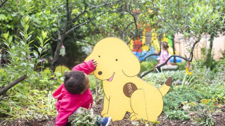 A baby looks at Spot the Dog in the Fairy Garden.